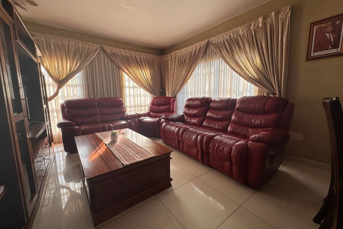 A comfortable living room featuring large format floor tiles and expansive window treatments, providing a bright and functional space for relaxation.