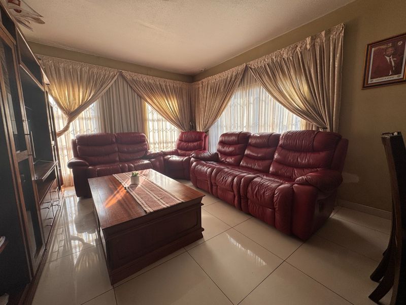 A comfortable living room featuring large format floor tiles and expansive window treatments, providing a bright and functional space for relaxation.