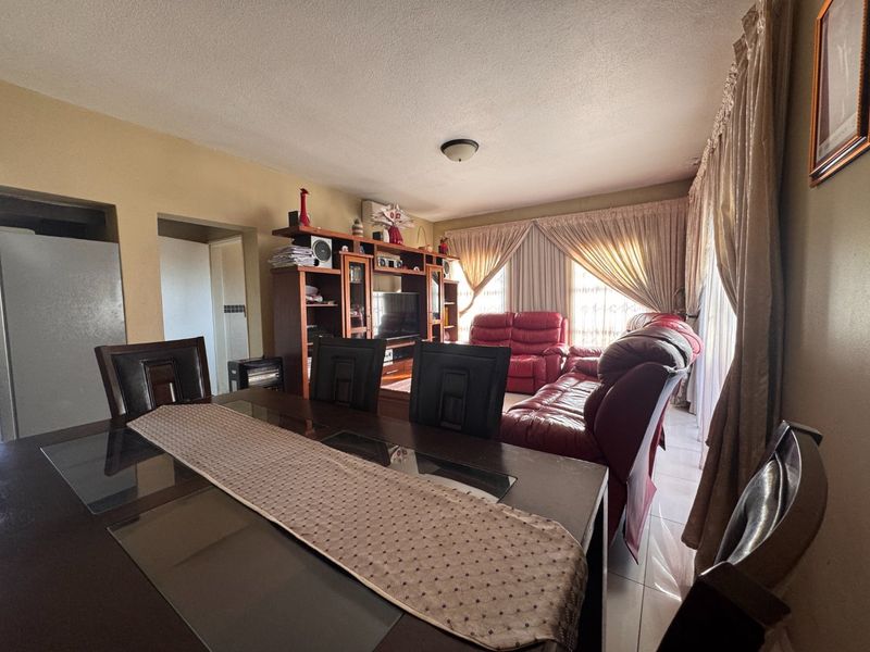 Open-plan living and dining area featuring tiled flooring and natural light through large windows.
