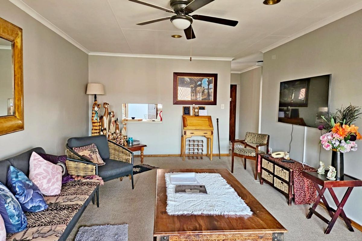A comfortable living room featuring a ceiling fan, recessed lighting, and a convenient pass-through window connecting to the adjacent space.