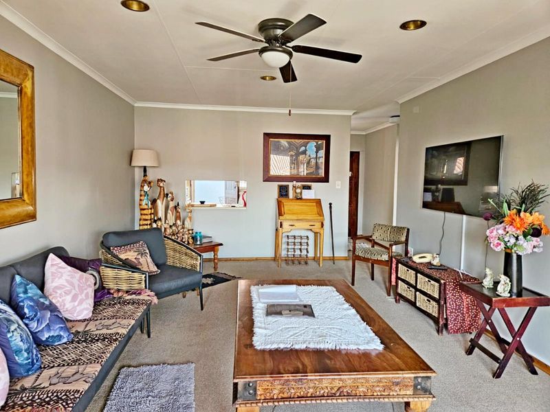 A comfortable living room featuring a ceiling fan, recessed lighting, and a convenient pass-through window connecting to the adjacent space.