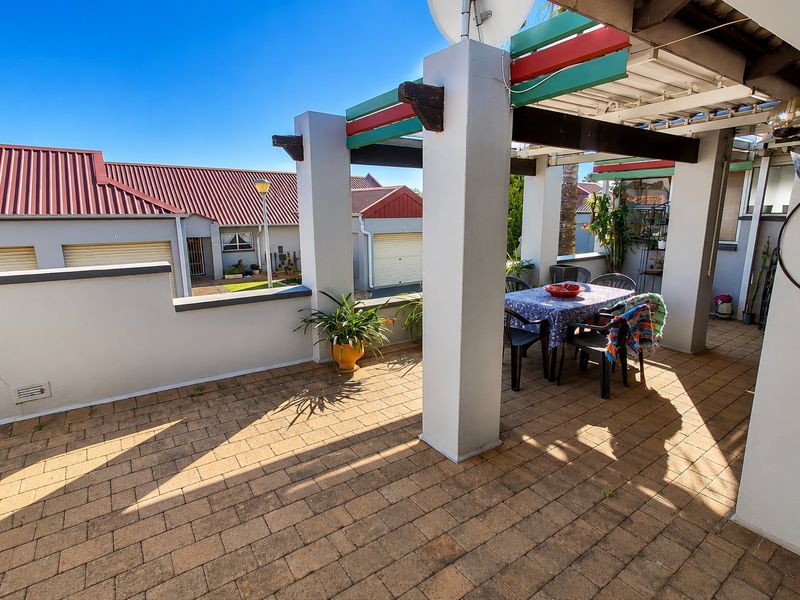 A covered outdoor patio area featuring paved flooring and a pergola structure, providing a functional space for outdoor dining.