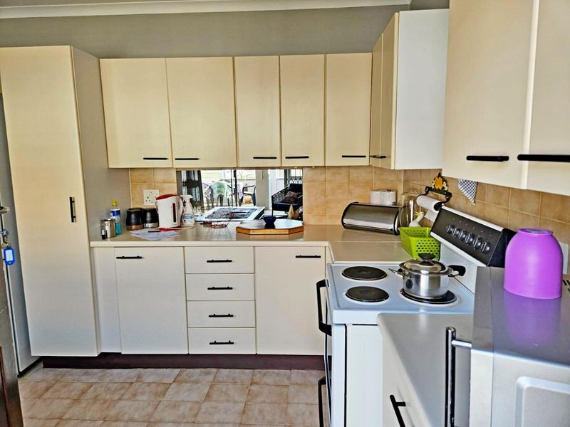A functional kitchen featuring laminate cabinetry, tiled backsplash, and an electric stove, offering a practical layout with potential for modern updates.