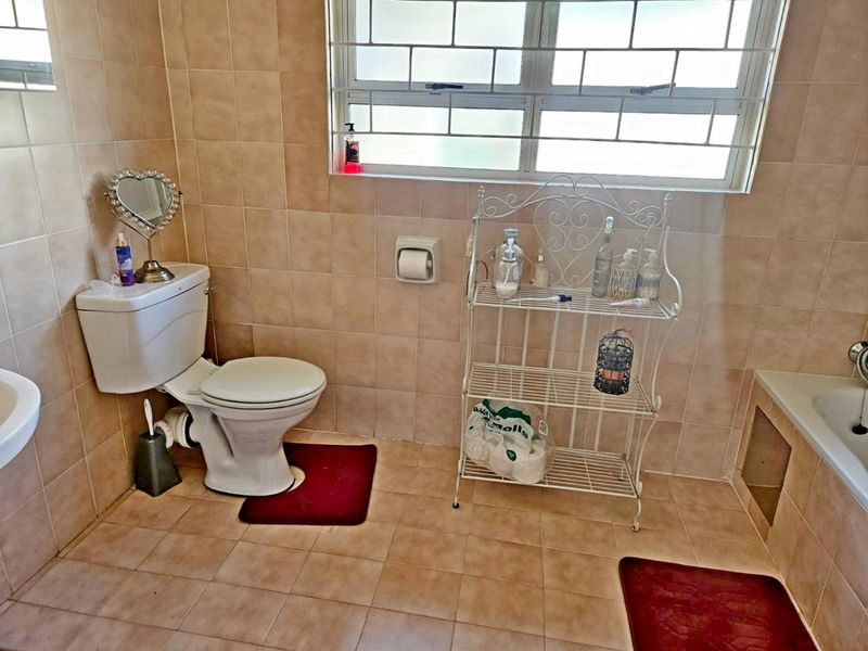 A functional bathroom featuring tiled walls and flooring, a standard toilet, and a bathtub with a missing side panel.