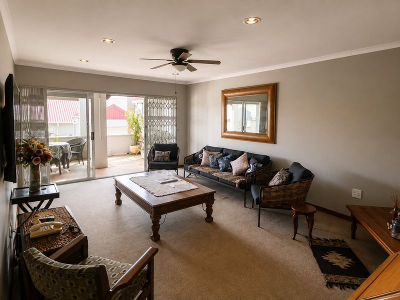 Spacious living room featuring neutral carpeting, recessed lighting, a ceiling fan, and large sliding glass doors providing access to an outdoor patio area.
