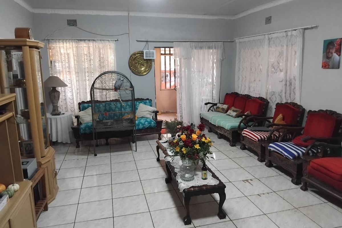 A spacious living room featuring tiled flooring, a ceiling fan, and an integrated air conditioning unit, with direct access to an outdoor area.