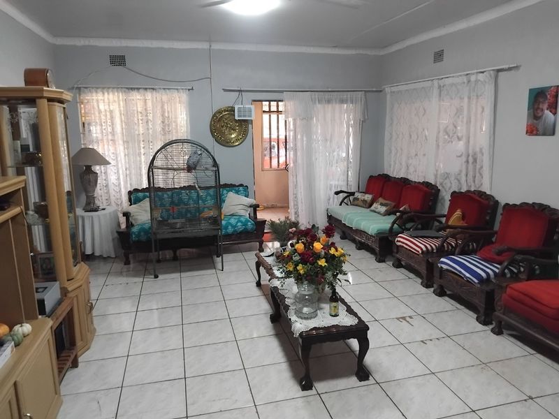 A spacious living room featuring tiled flooring, a ceiling fan, and an integrated air conditioning unit, with direct access to an outdoor area.