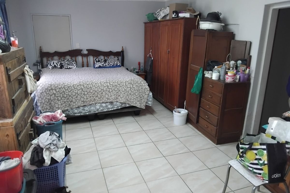 A spacious bedroom featuring tiled flooring and decorative ceiling cornicing, offering a functional layout with ample space for bedroom furniture.