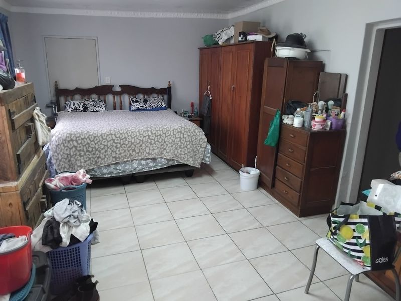 A spacious bedroom featuring tiled flooring and decorative ceiling cornicing, offering a functional layout with ample space for bedroom furniture.