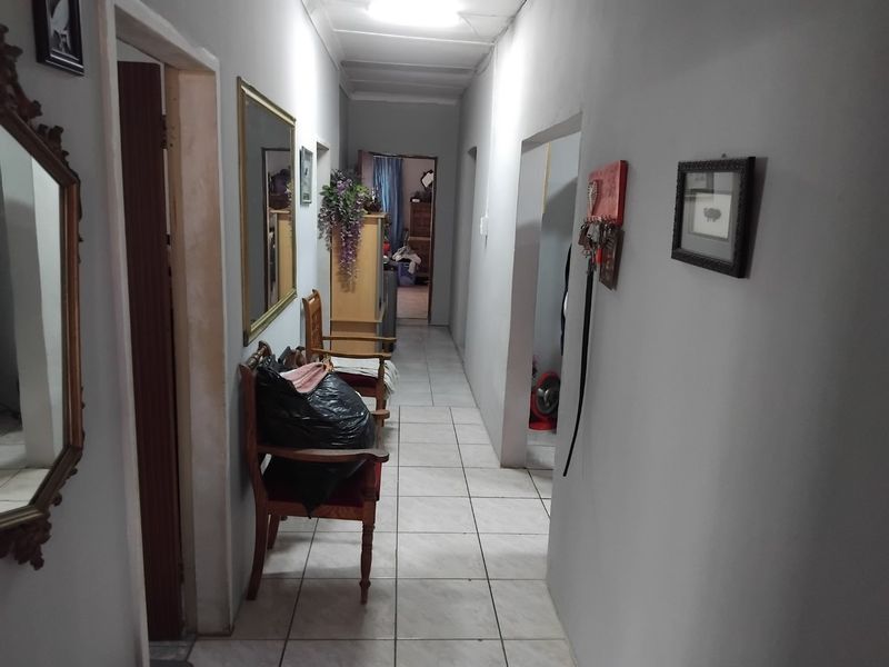 A functional interior hallway featuring ceramic floor tiles and access to multiple rooms, requiring minor cosmetic updates to improve the overall aesthetic.