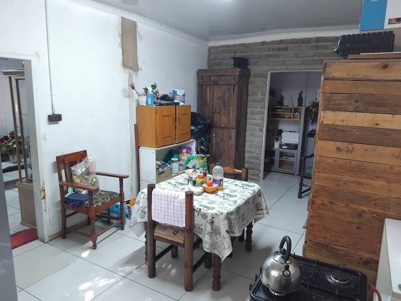 A kitchen area featuring tiled floors, exposed brickwork, and crown molding, currently requiring significant cosmetic updates and wall repairs.