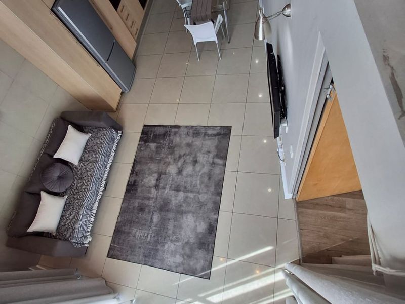 A high-angle view of a modern open-plan living and kitchen area featuring tiled floors, sleek cabinetry, and integrated kitchen appliances.