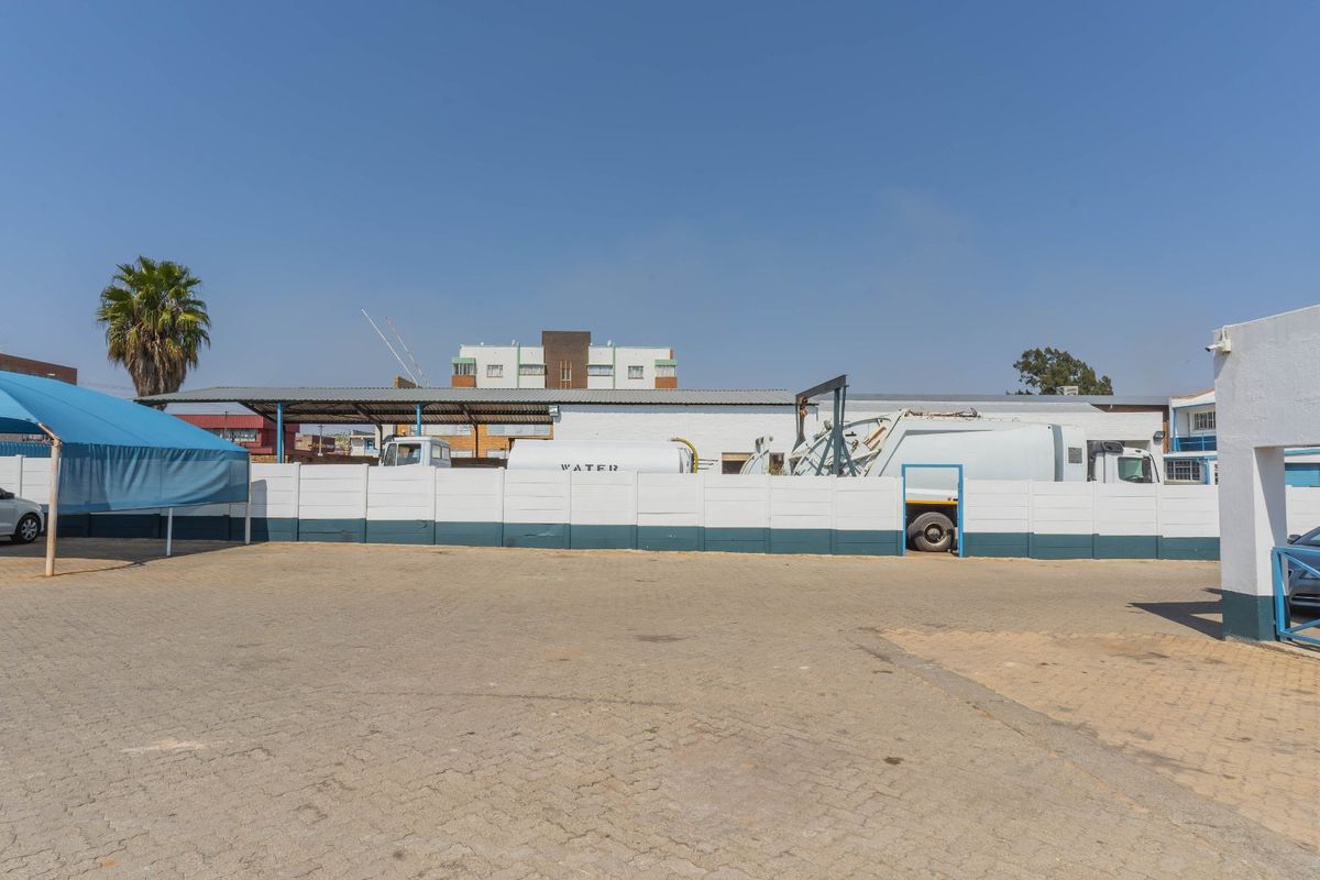 Spacious industrial yard featuring paved ground, a perimeter wall, and a covered parking area suitable for commercial vehicle storage.