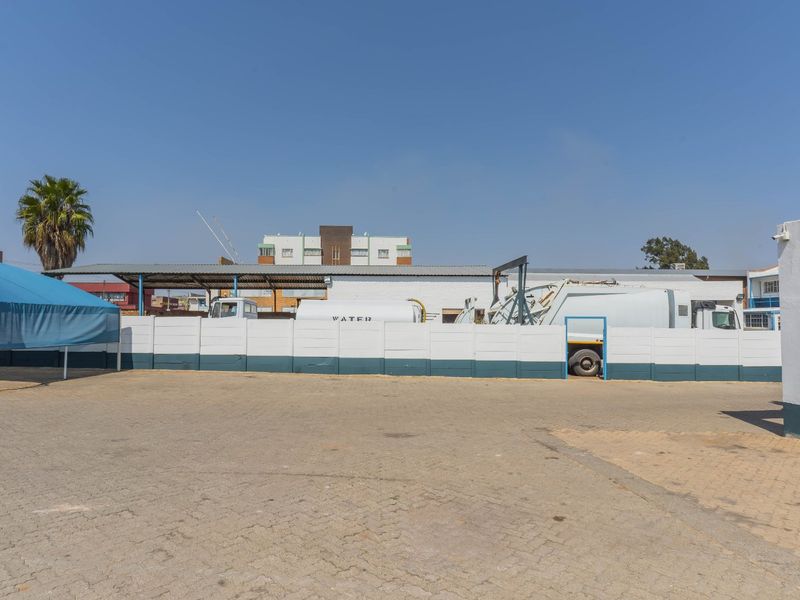 Spacious industrial yard featuring paved ground, a perimeter wall, and a covered parking area suitable for commercial vehicle storage.