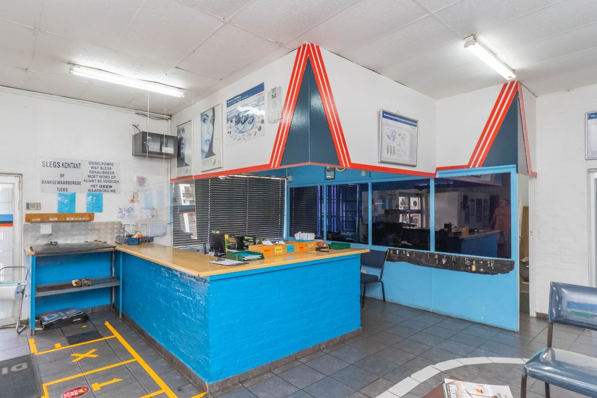 Industrial reception area featuring a built-in service counter, tiled flooring, and glass partition wall, suitable for a workshop or commercial office space.