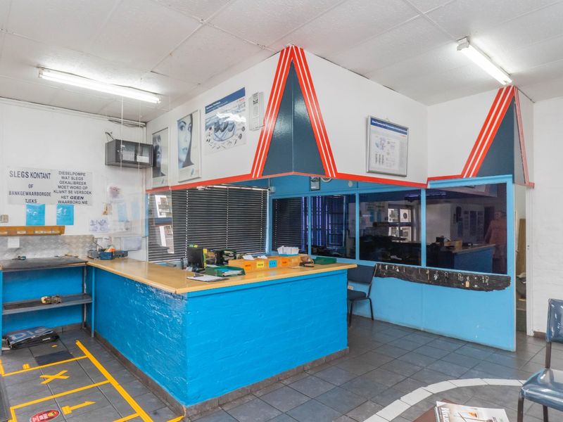 Industrial reception area featuring a built-in service counter, tiled flooring, and glass partition wall, suitable for a workshop or commercial office space.