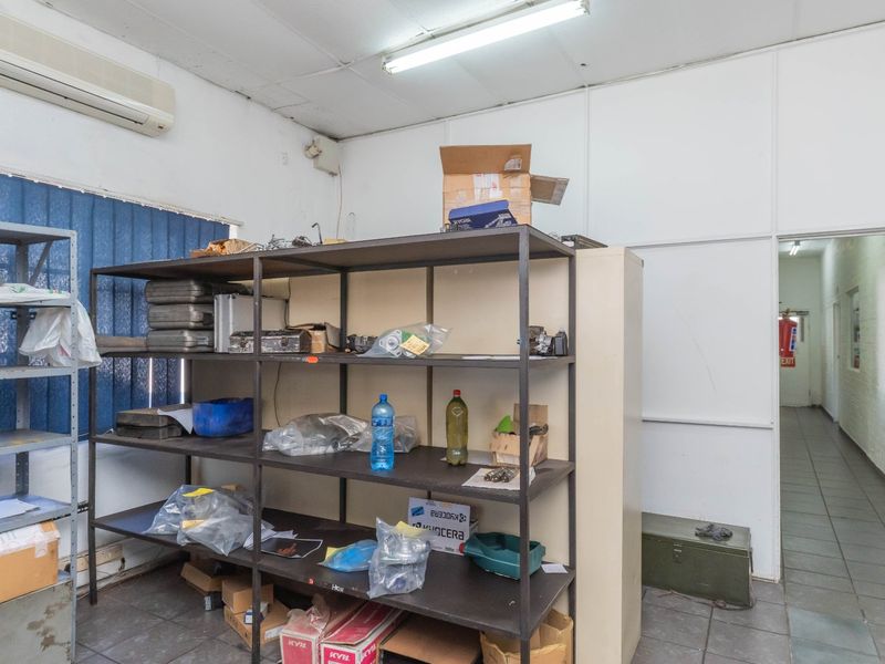 A functional industrial utility or storage space featuring tiled flooring, partition walls, and a wall-mounted air conditioning unit.