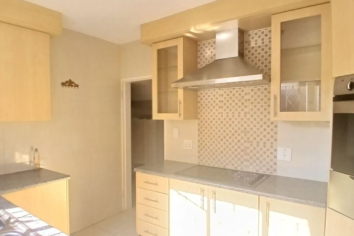 A functional kitchen featuring light wood cabinetry, mosaic tile backsplash, integrated stainless steel appliances, and durable tiled flooring.