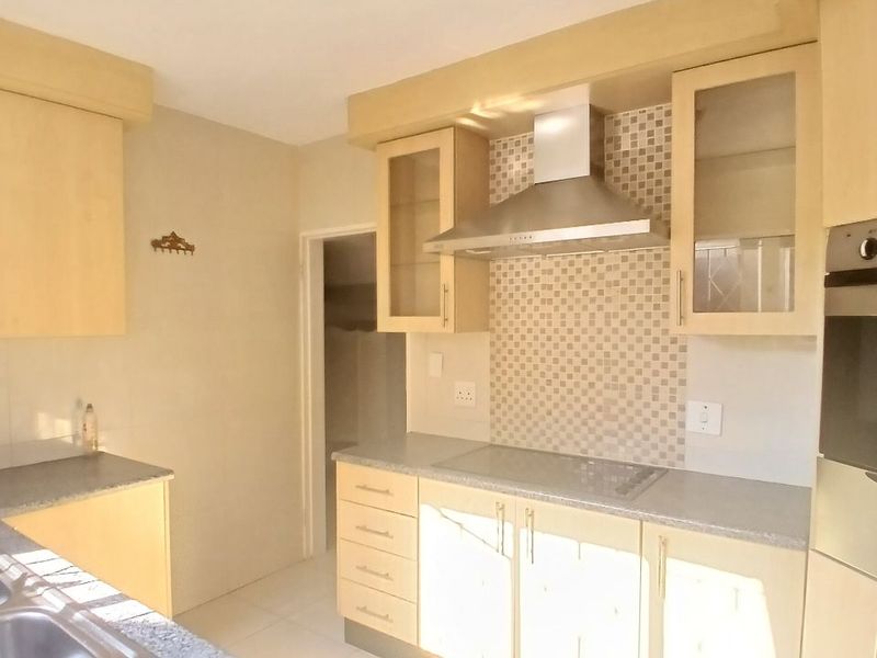 A functional kitchen featuring light wood cabinetry, mosaic tile backsplash, integrated stainless steel appliances, and durable tiled flooring.