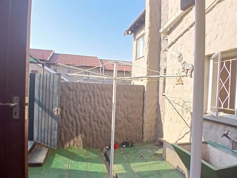 A rear courtyard area featuring a concrete wash trough, rotary clothesline, and textured wall finish, providing a functional outdoor utility space.