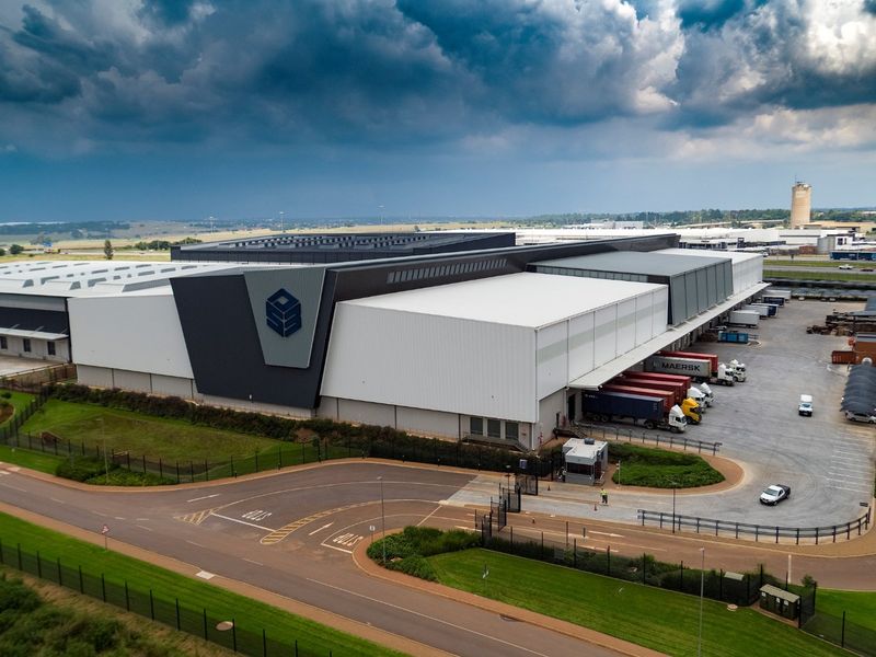 Aerial view of a large industrial warehouse facility featuring extensive loading docks, secure perimeter fencing, and a dedicated gatehouse entrance.