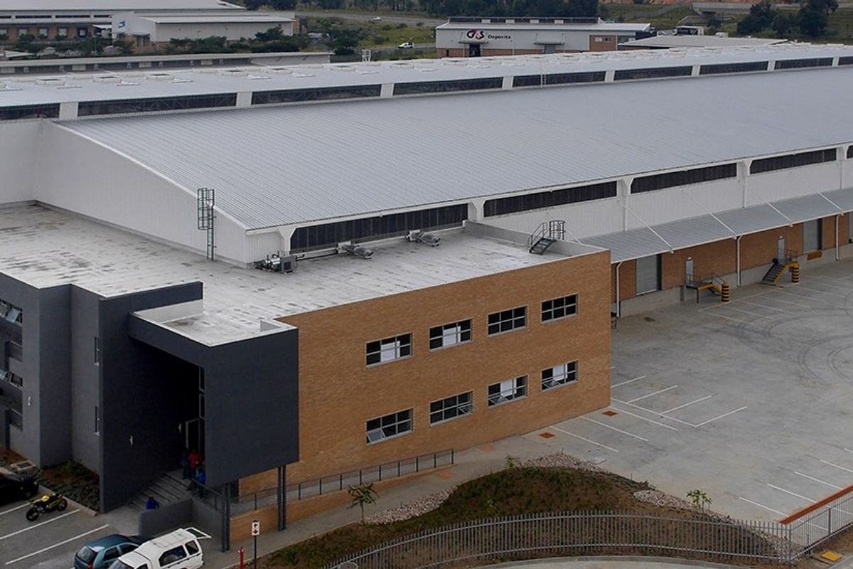 Aerial view of a large industrial warehouse facility featuring a metal roof, extensive concrete yard, loading bays, and integrated office block.
