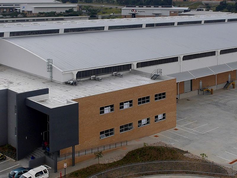 Aerial view of a large industrial warehouse facility featuring a metal roof, extensive concrete yard, loading bays, and integrated office block.