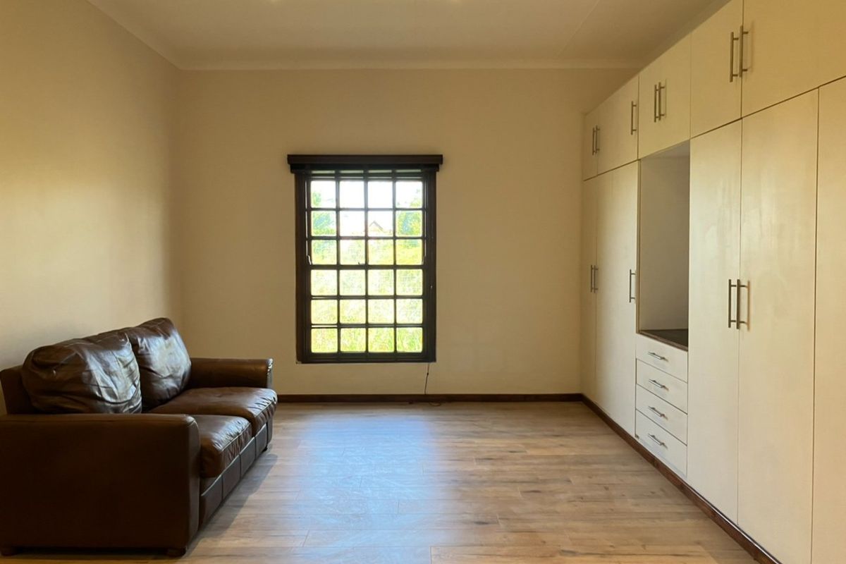 A well-maintained bedroom featuring extensive built-in cabinetry, modern laminate flooring, and recessed downlighting, offering a clean and functional living space.
