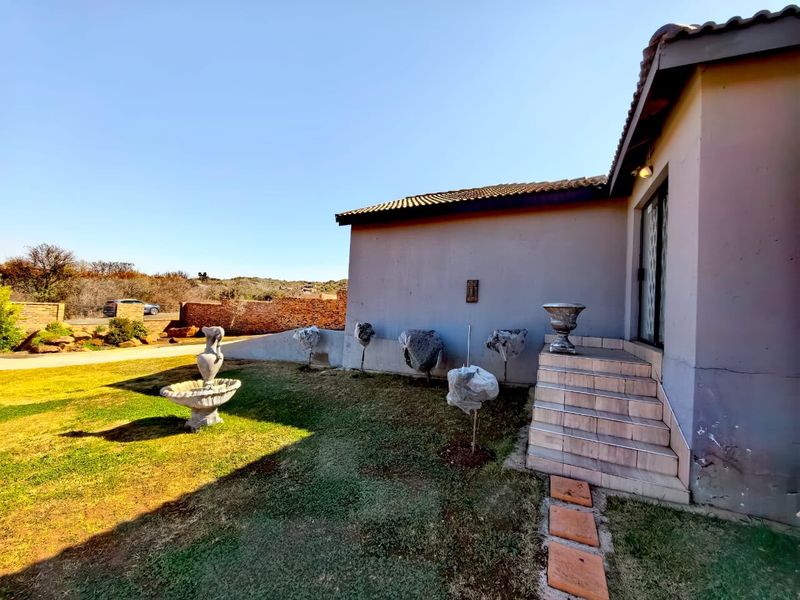 Rear exterior view of the property featuring a tiled staircase, concrete walling, and a brick boundary wall with surrounding garden space.