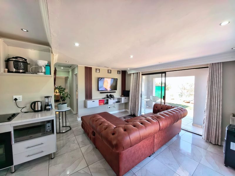Open-plan living area featuring tiled floors, recessed lighting, a built-in media console, and sliding glass doors leading to an outdoor patio space.