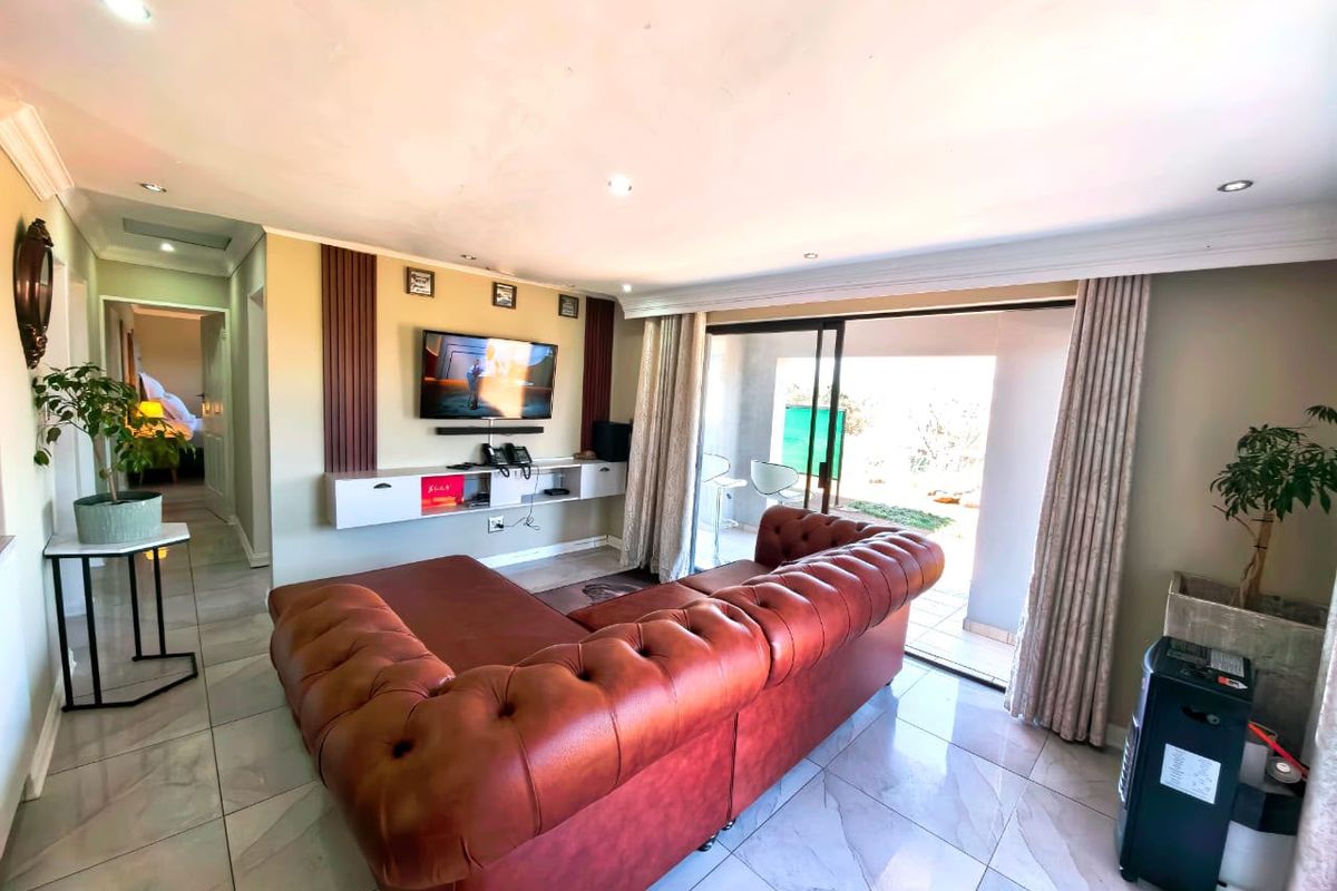 Spacious living room featuring tiled flooring, recessed lighting, and a built-in media console, with direct access to an outdoor patio through sliding glass doors.