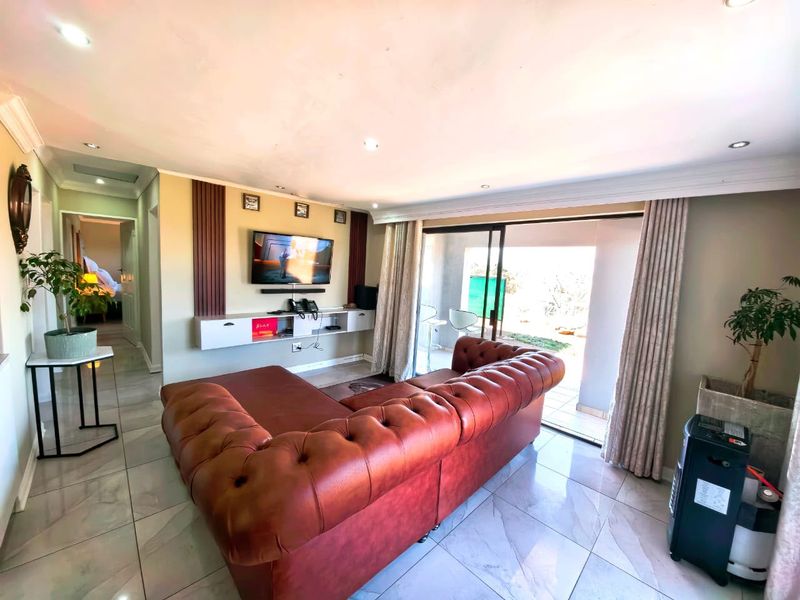 Spacious living room featuring tiled flooring, recessed lighting, and a built-in media console, with direct access to an outdoor patio through sliding glass doors.