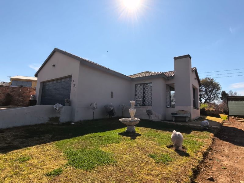 Front elevation of a single-story residential house featuring a single garage, tiled roof, and chimney, set on a landscaped plot.