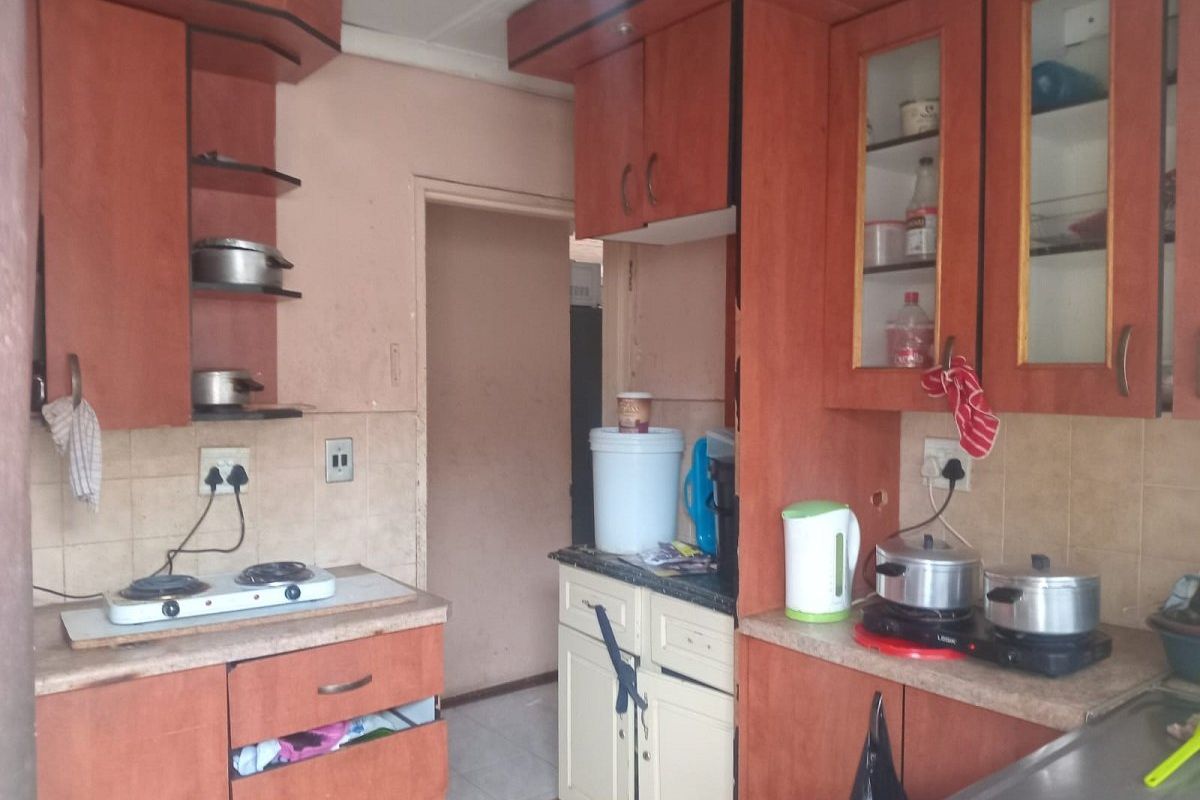 A dated kitchen featuring laminate cabinetry, tiled backsplash, and laminate countertops, requiring cosmetic updates to improve functionality and aesthetic appeal.