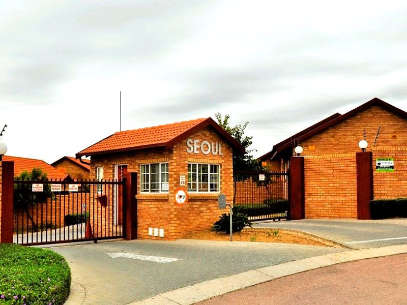The entrance to the residential complex features a brick guard house, secure gated access, and perimeter walling with electric fencing.