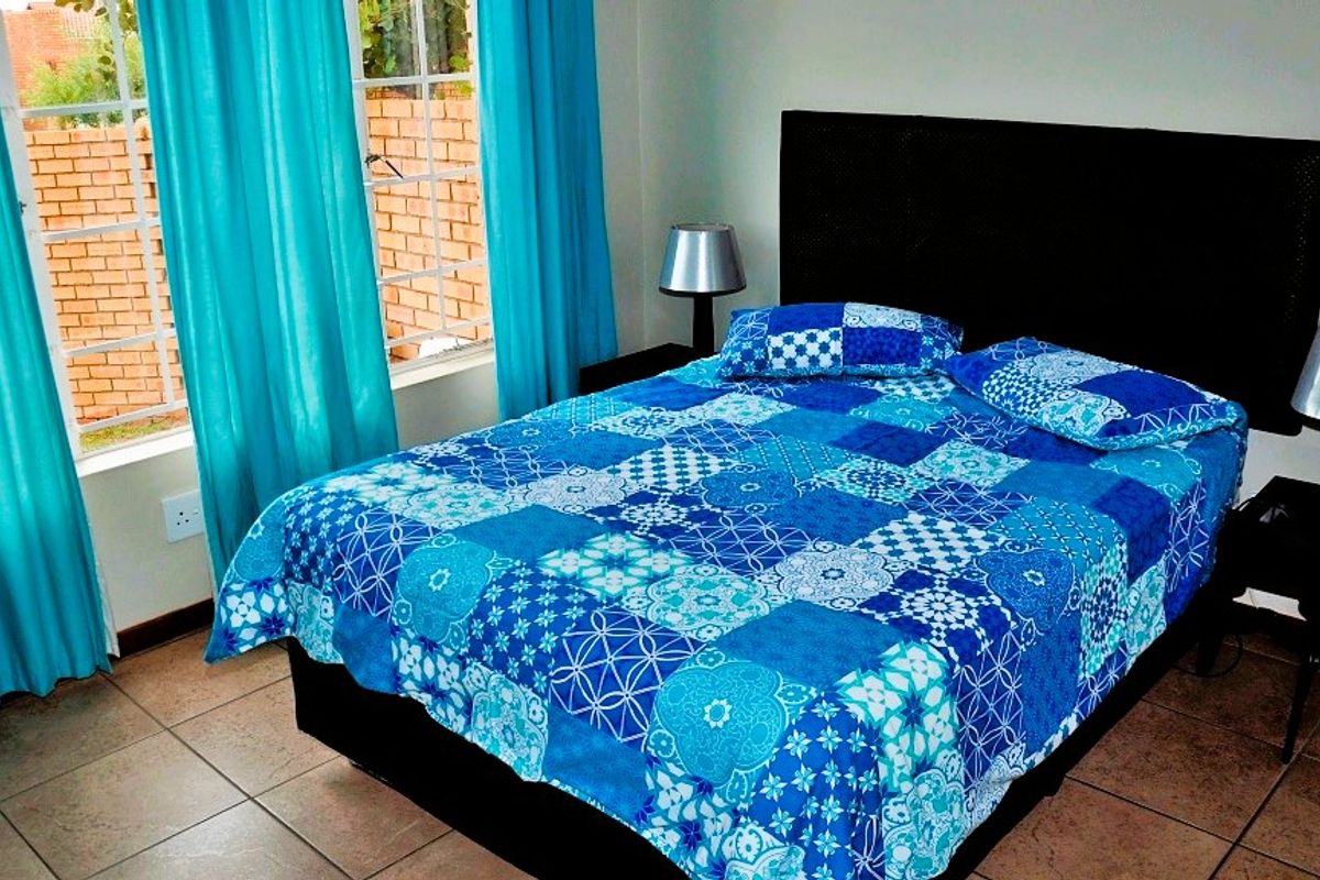 A bedroom featuring tiled flooring and a window with security bars, providing a functional space with natural light.