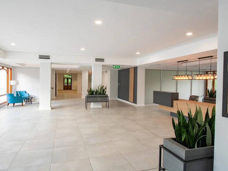Spacious commercial building entrance featuring a modern reception desk, tiled flooring, and recessed lighting, creating a professional and welcoming atmosphere.