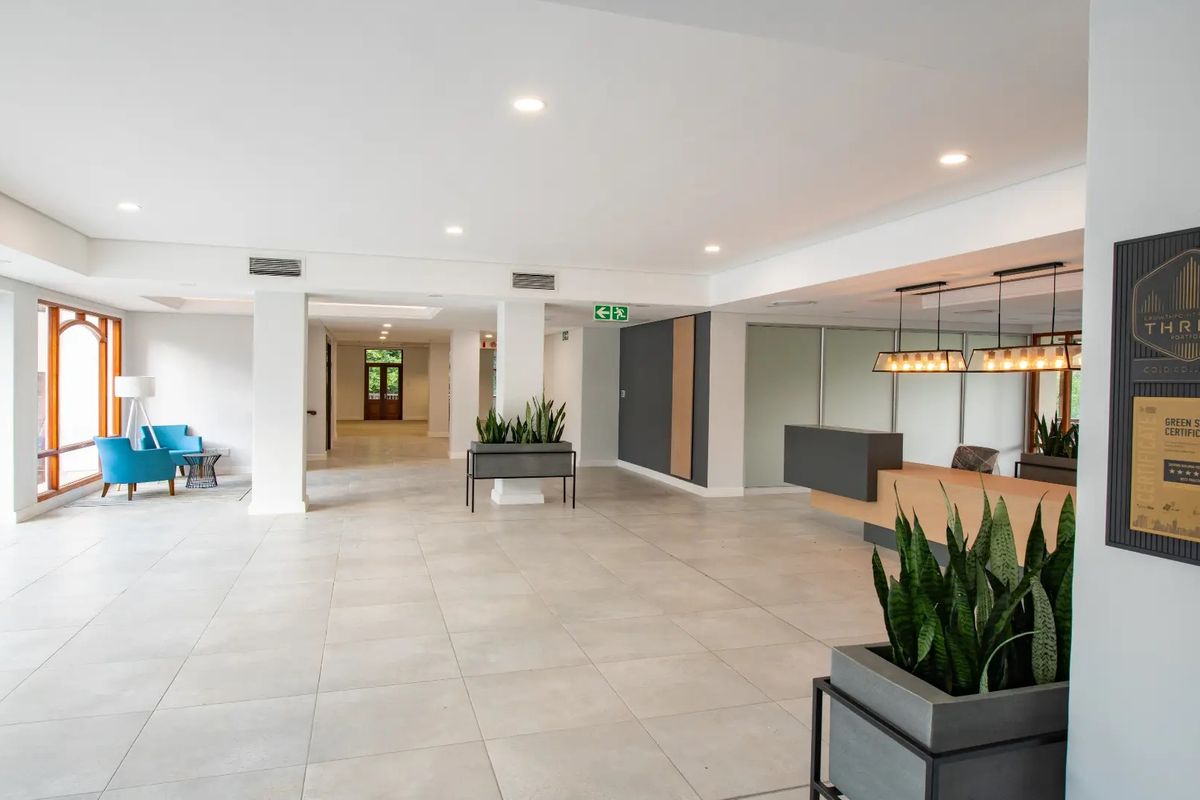 Spacious commercial building entrance featuring a modern reception desk, tiled flooring, and recessed lighting, creating a professional and welcoming atmosphere.