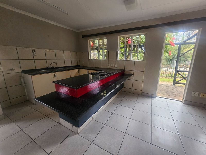 A functional kitchen featuring granite countertops, a built-in hob, tiled flooring, and direct access to the outdoor area.