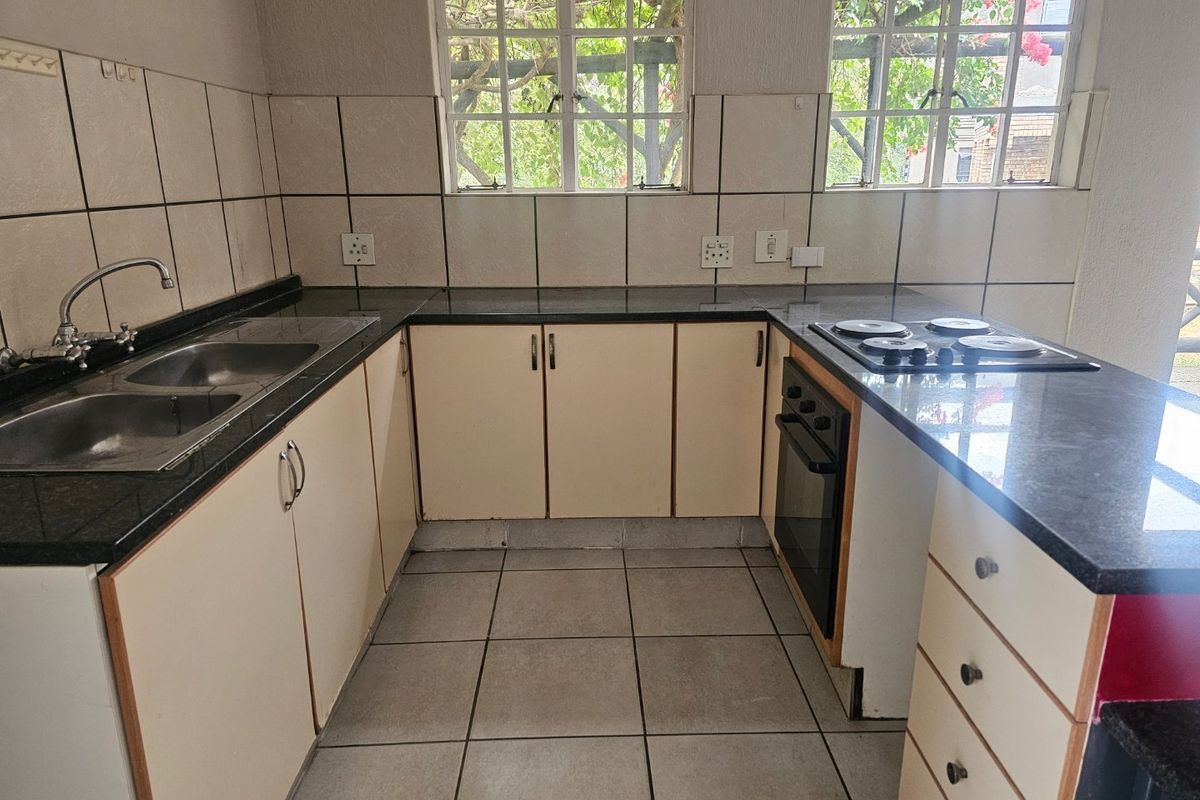 A functional kitchen featuring granite countertops, built-in cabinetry, a double basin sink, and an integrated oven with an electric hob.
