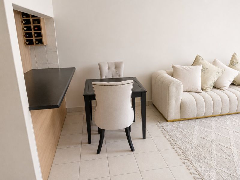 An open-plan living and dining area featuring tiled flooring, a built-in wine rack, and a functional laminate countertop serving as a breakfast bar.