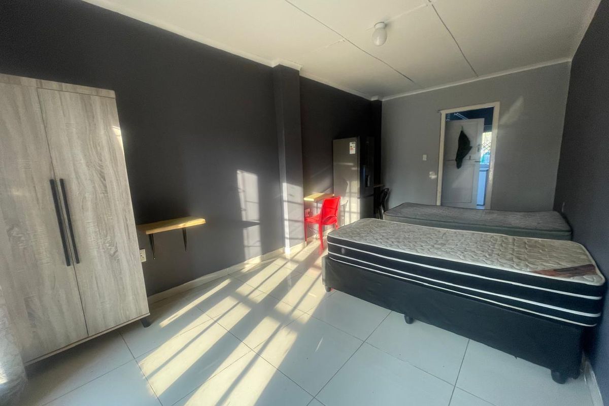 A functional bedroom featuring tiled flooring and neutral wall finishes, providing a simple and practical living space.