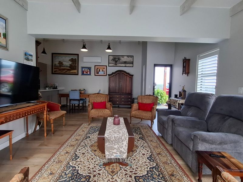 Spacious open-plan living area featuring exposed ceiling beams, laminate flooring, and plantation shutters, creating a bright and comfortable atmosphere.