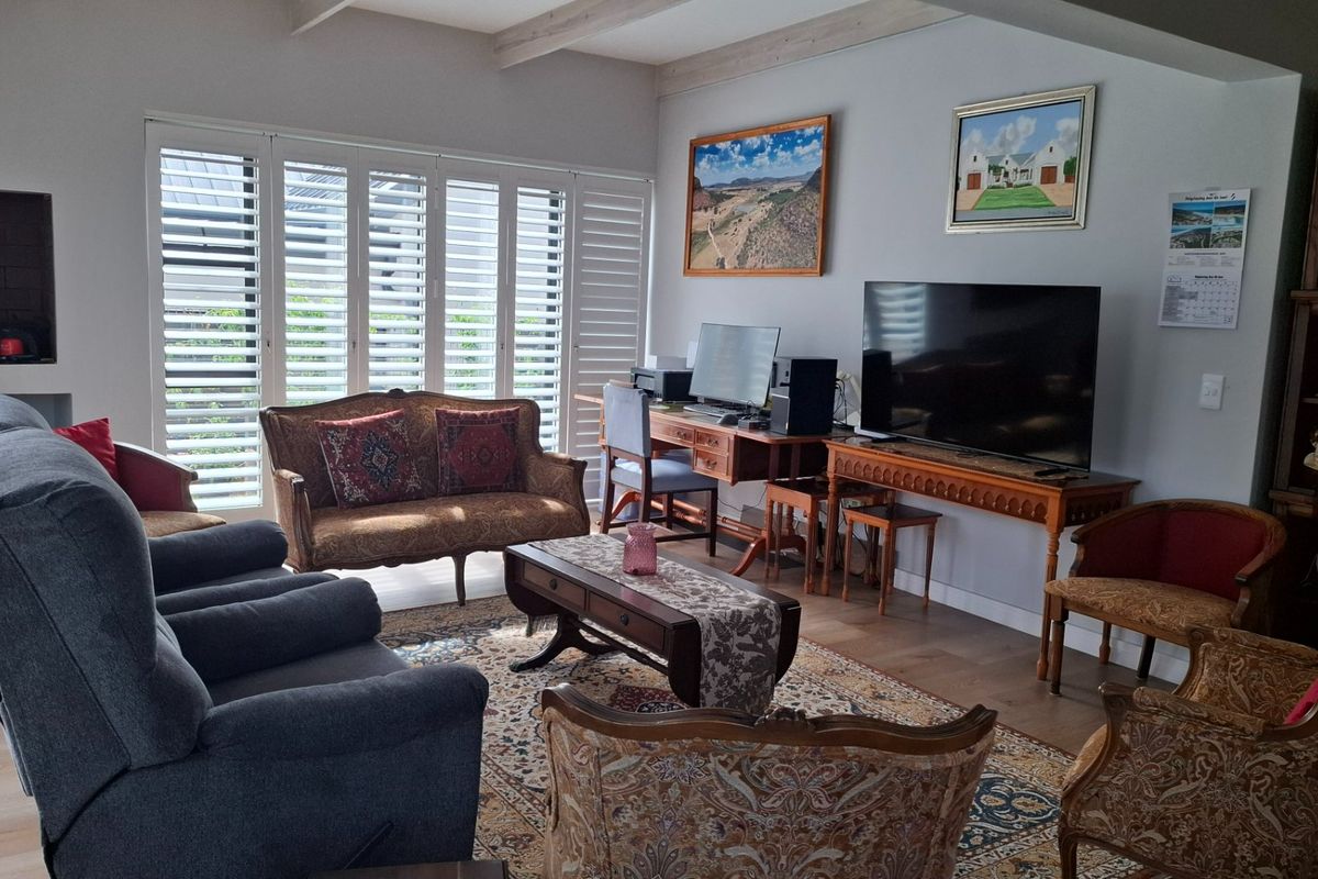 Spacious living room featuring exposed timber ceiling beams, laminate flooring, and plantation shutters, providing a bright and comfortable atmosphere.