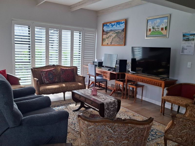 Spacious living room featuring exposed timber ceiling beams, laminate flooring, and plantation shutters, providing a bright and comfortable atmosphere.