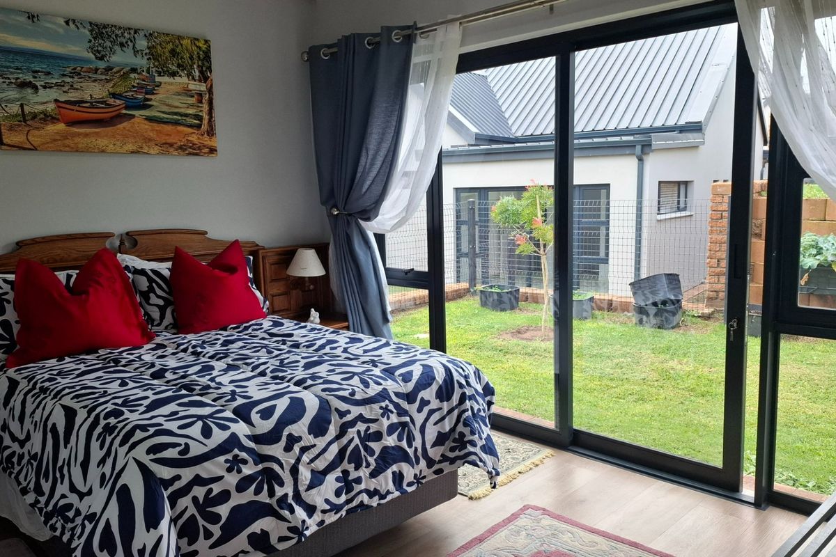 A well-maintained bedroom featuring laminate flooring and large sliding glass doors that provide direct access to the rear garden.