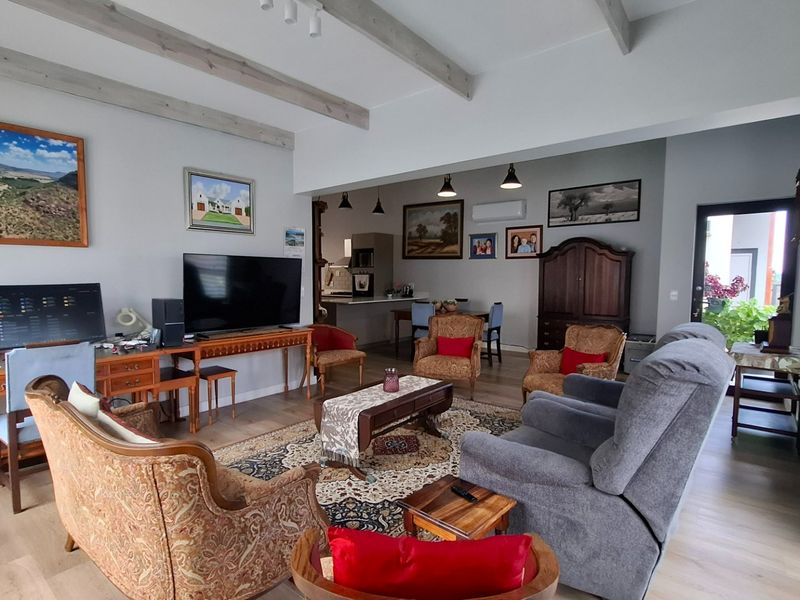 Spacious open-plan living area featuring exposed ceiling beams, laminate flooring, and a split-system air conditioner, seamlessly connecting to the kitchen and dining space.