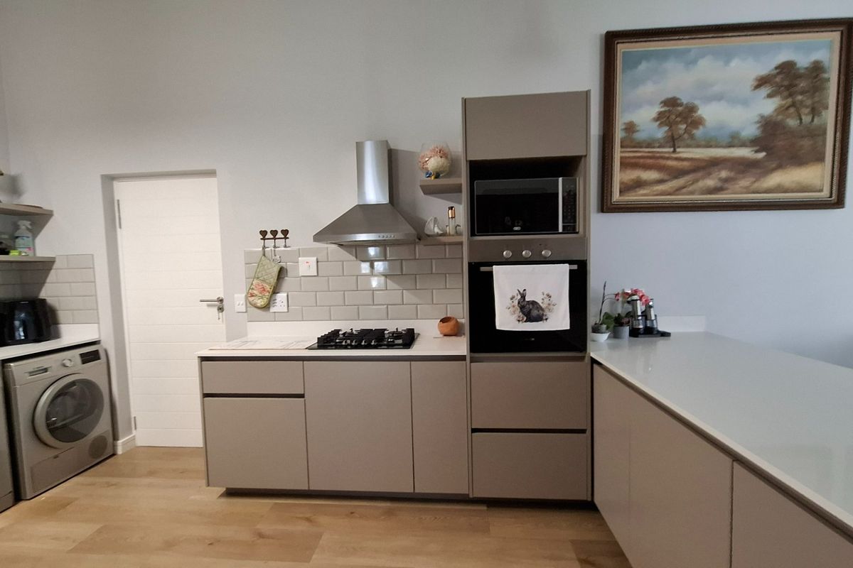 Modern kitchen featuring sleek cabinetry, subway tile backsplash, built-in oven, microwave, and gas hob with integrated laundry appliances.