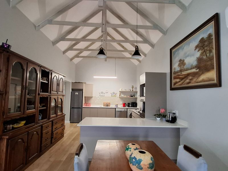 Spacious open-plan kitchen and dining area featuring a high vaulted ceiling with exposed timber trusses and modern cabinetry.