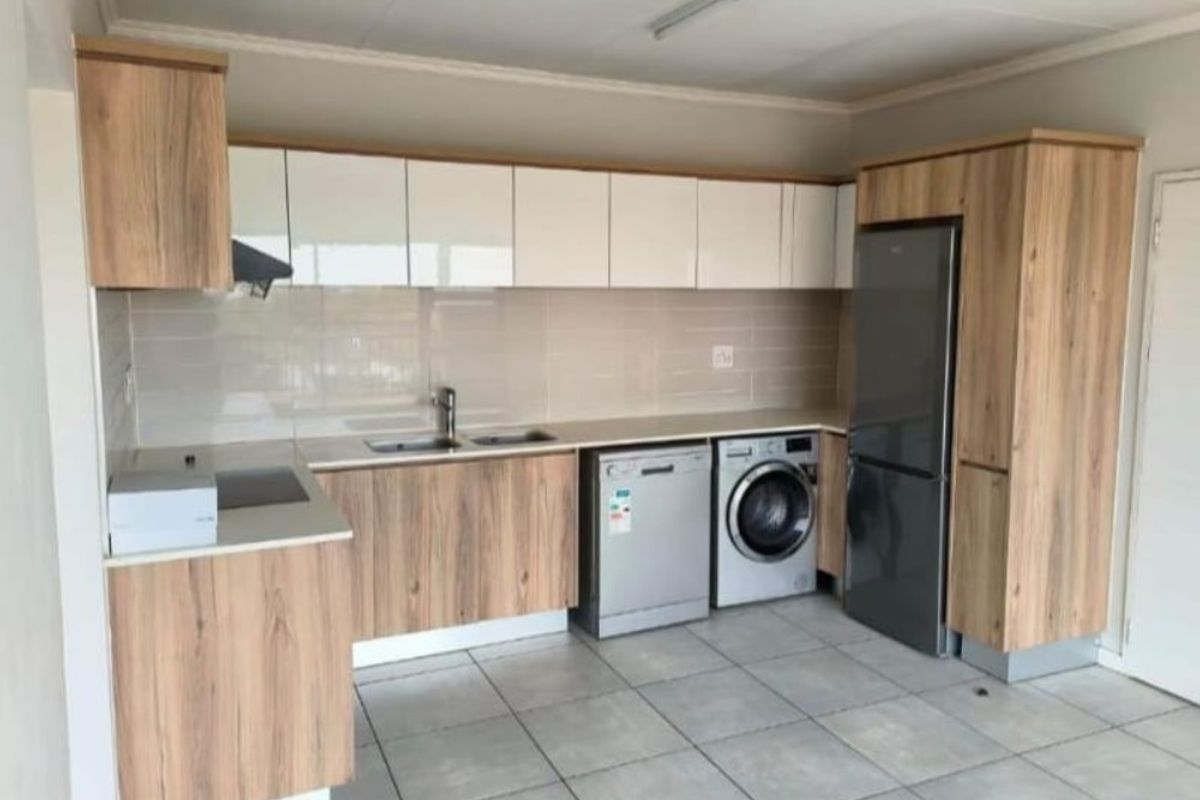 Modern kitchen featuring wood-grain and white cabinetry, tiled flooring, integrated sink, and dedicated spaces for appliances.